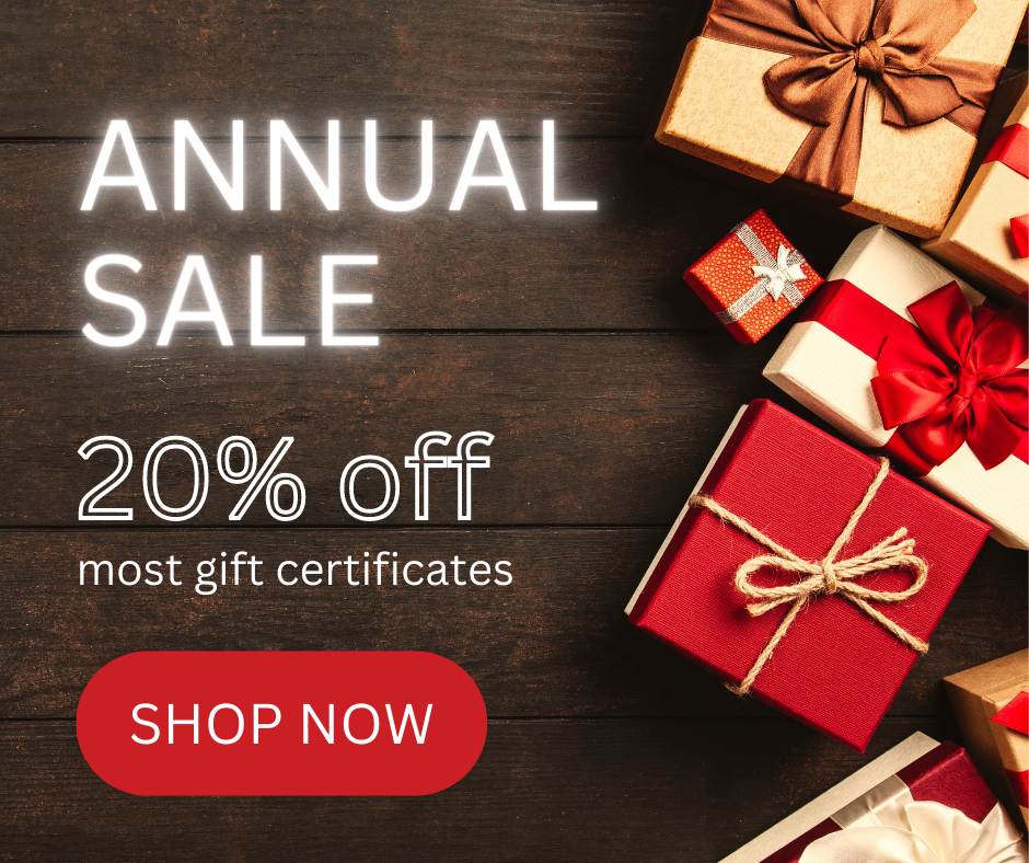 A picture of a dark wood floor with presents wrapped in red, cream, and gold on the right, and text on the left that reads: Annual Sale, 20% off most gift certificates, Shop Now.